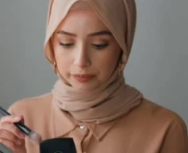 A person in hijab applying makeup.