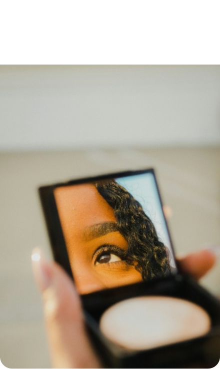 A hand holding a small mirror, reflecting an eye.